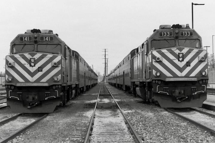 Two trains face each other on parallel tracks, with power lines visible in the distance.