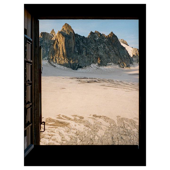 A glacier and mountain range are visible through an open window.