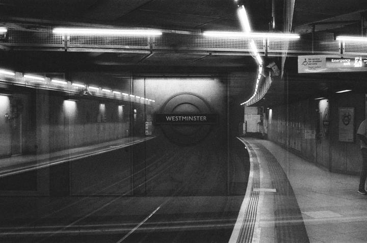 A person stands on a subway platform with a "Westminster" sign on the wall.
