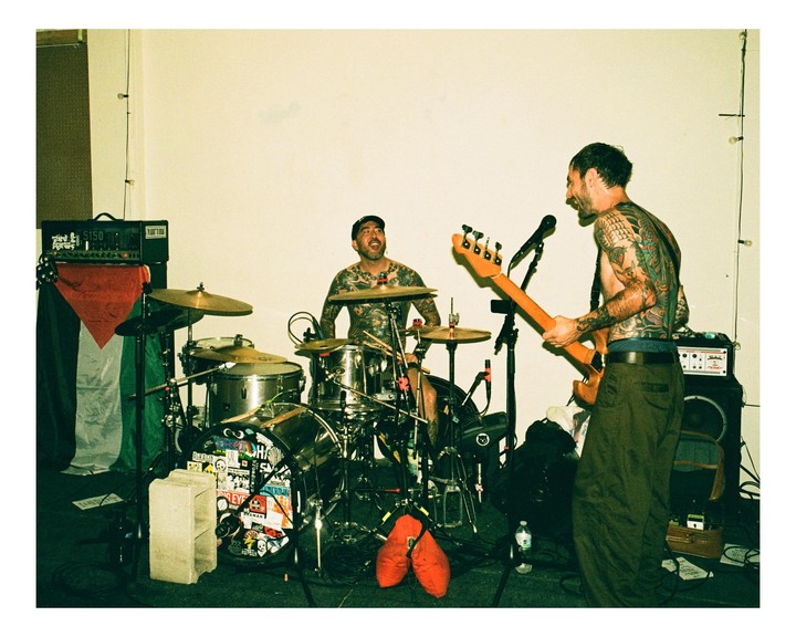 Two men with tattoos are playing musical instruments on a stage.