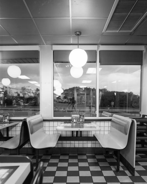A diner interior with booths, tables, and a checkered floor is visible through a window.