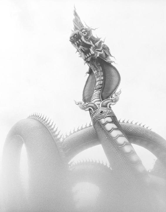 A large dragon statue with an open mouth and sharp teeth rises from a hazy, light-colored background.
