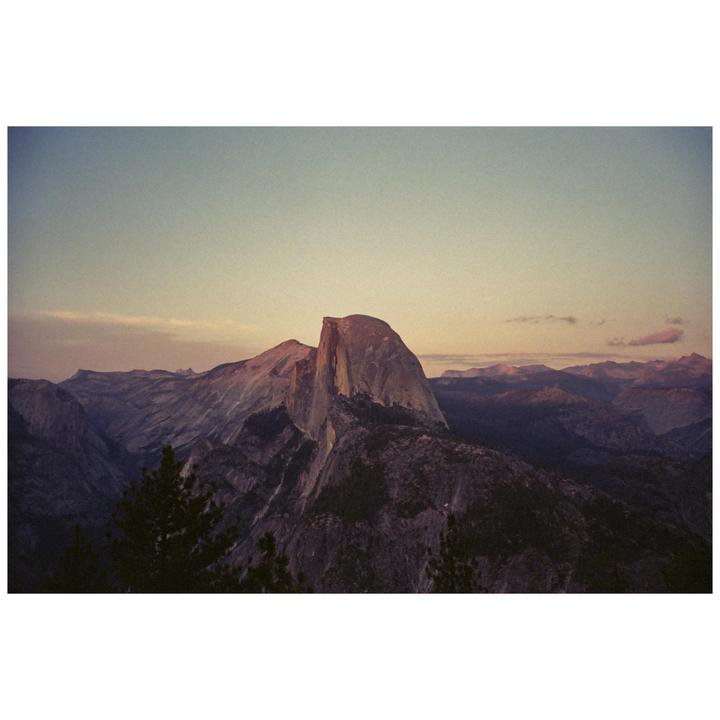 A large rock formation dominates the landscape under a soft, colorful sky.