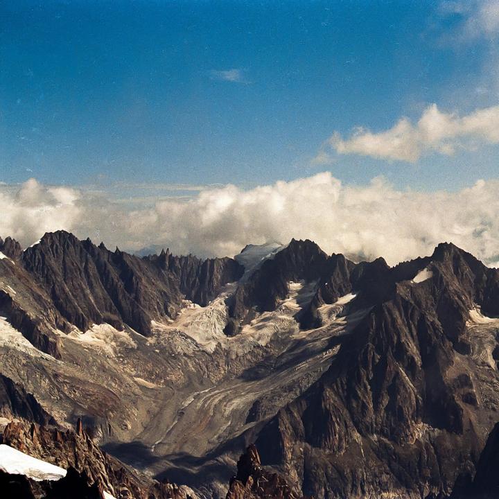 A mountain range with snow and clouds is visible under a blue sky.