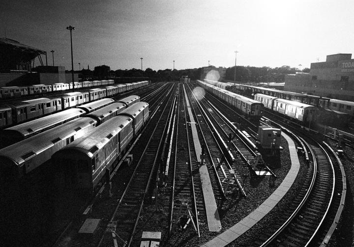 A high-angle black and white shot shows multiple trains parked on many tracks in a train yard.