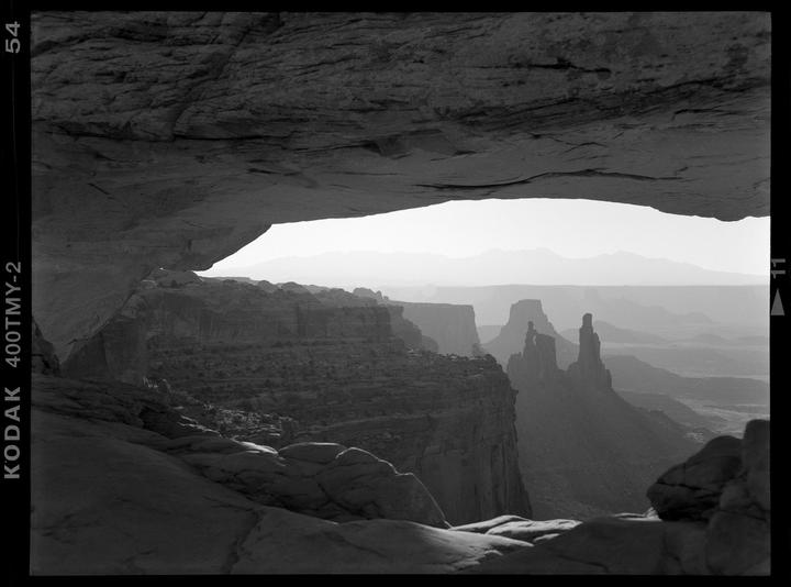 A landscape of canyons and mountains is visible through a rock arch.