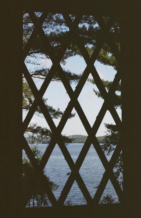 A lake and distant hills are visible through a diamond-patterned window.
