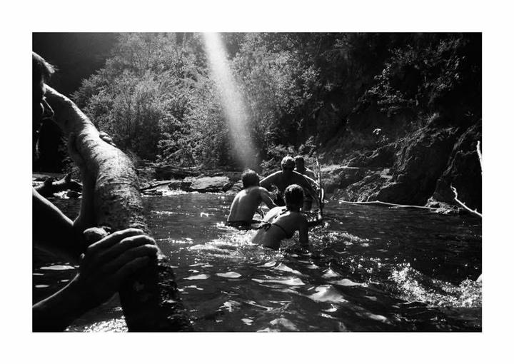 A group of people are in a river with a beam of light shining down from above.