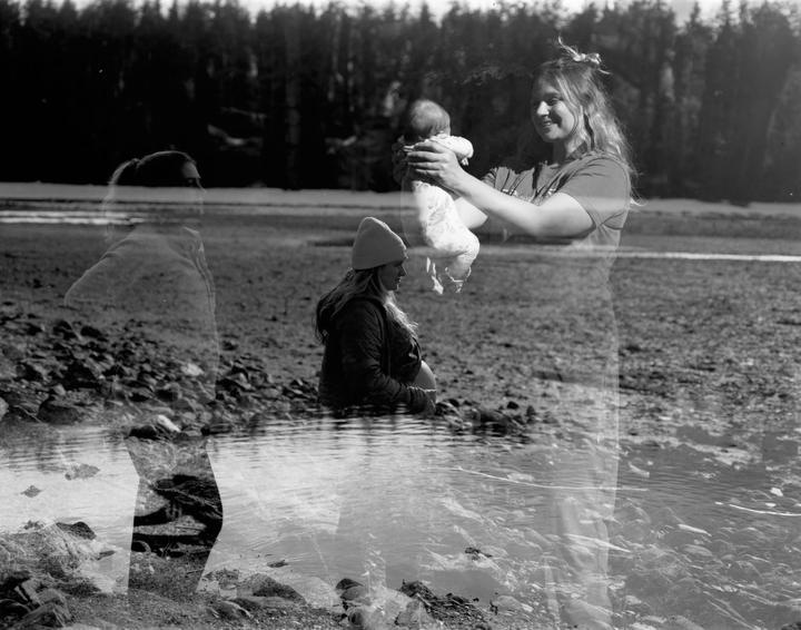 A triple exposure shows a woman at different stages of pregnancy and with her newborn baby by a body of water.