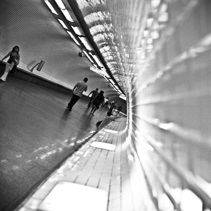 People walk through a brightly lit, curved underground tunnel.