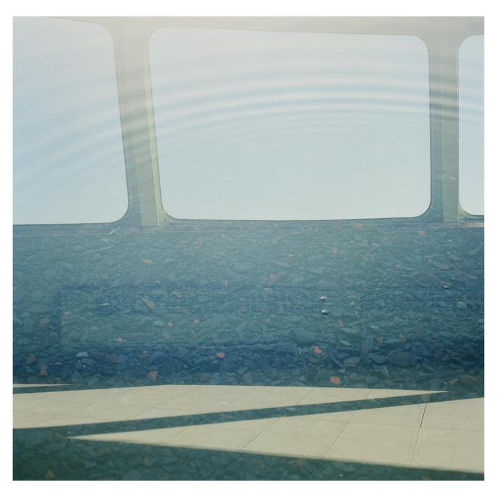 A double exposure shows a ferry window and a wall of rubble with shadows on the ground.