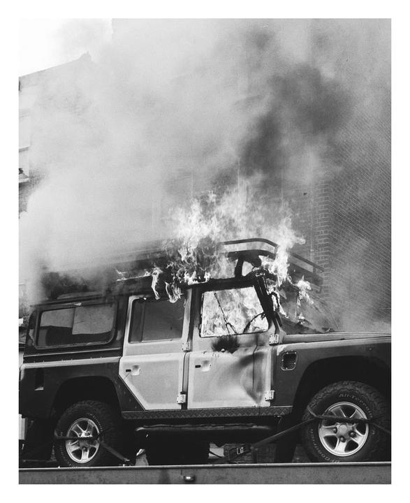 A vehicle is engulfed in flames and smoke on a street in London.