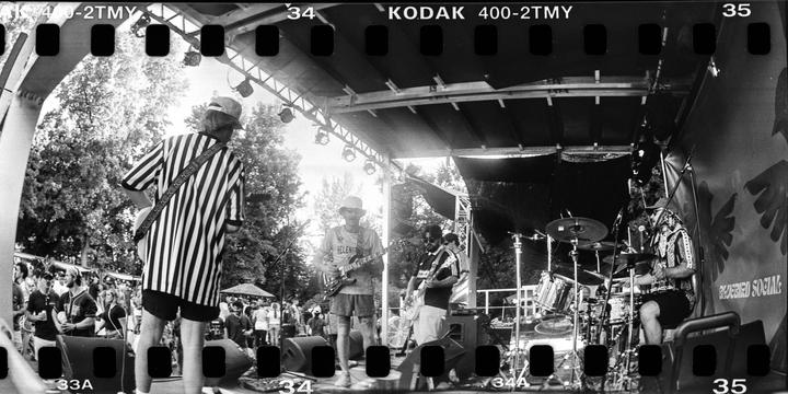 A band performs on an outdoor stage with a crowd of people watching.