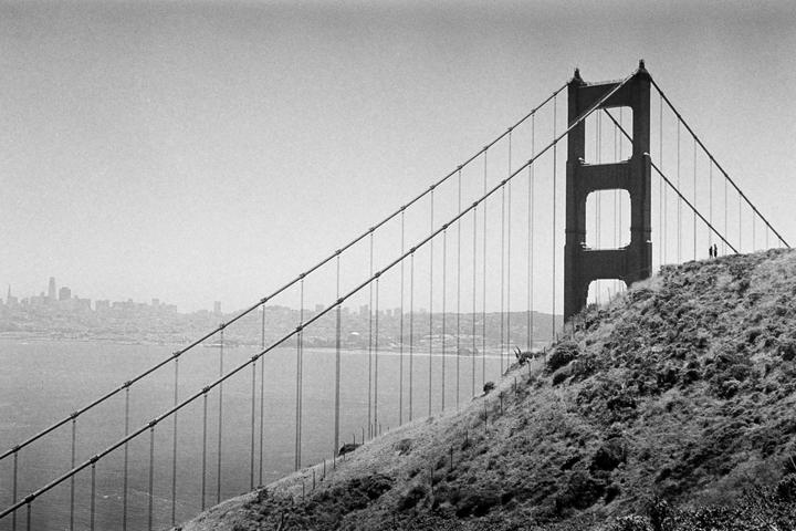 A black and white photograph shows the Golden Gate Bridge with a city skyline in the background.